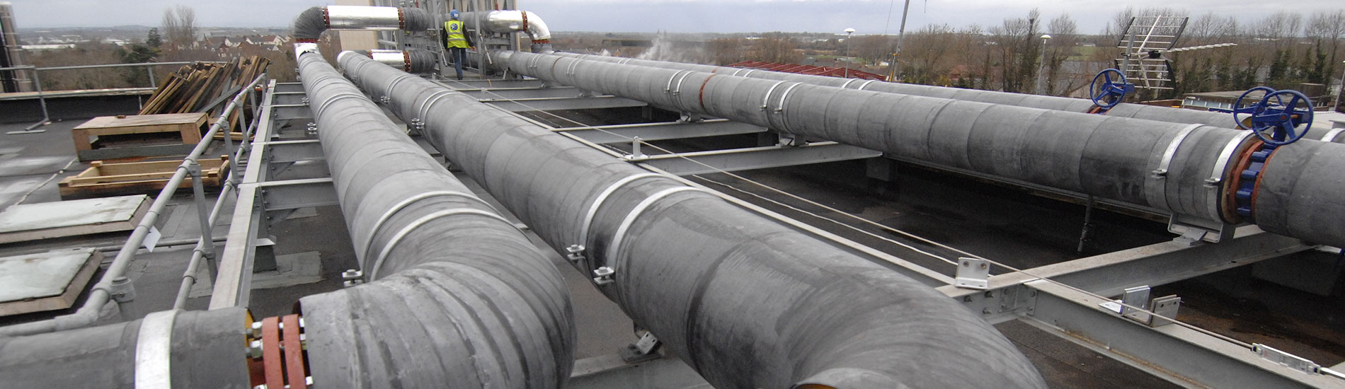 Insulated pipework runs across a rooftop installation